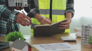 Planları elinde tutan ve evde çalışan mühendis.