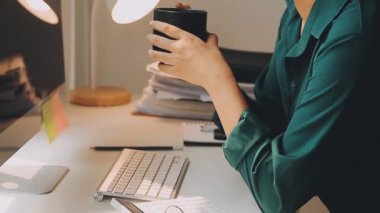 Kadın çay içiyor ve evde bilgisayar kullanıyor.