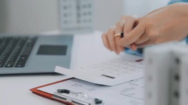 İş kadını ofiste dizüstü bilgisayar ve hesap makinesiyle çalışıyor.