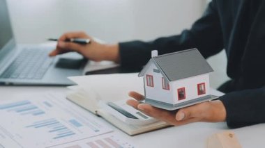 İş adamı konsepti hesap makinesinde çalışıyor, bilgisayarında ev modeli var..