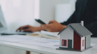 İş adamı konsepti hesap makinesinde çalışıyor, bilgisayarında ev modeli var..