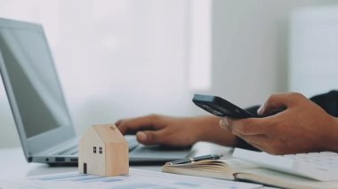 İş adamı konsepti hesap makinesinde çalışıyor, bilgisayarında ev modeli var..