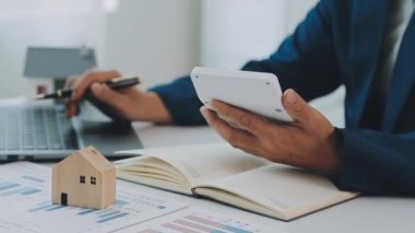 İş adamı konsepti hesap makinesinde çalışıyor, bilgisayarında ev modeli var..