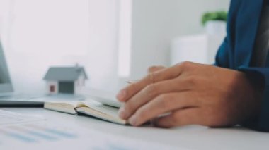 İş adamı konsepti hesap makinesinde çalışıyor, bilgisayarında ev modeli var..