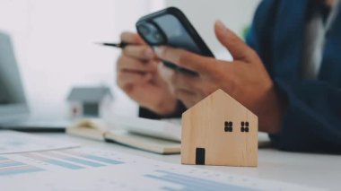 İş adamı konsepti hesap makinesinde çalışıyor, bilgisayarında ev modeli var..