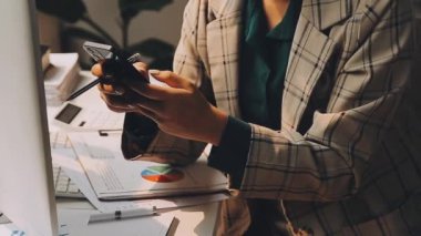 Genç bir iş kadını, iş ve finans kavramlarını ön plana çıkaran bir fon ile çağdaş bir ofiste çalışırken resmedilir..