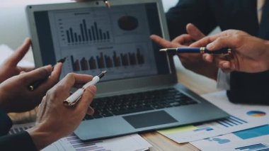 İş adamları yeni projeyi modern ofiste dizüstü bilgisayar ve iş belgeleriyle tartışıyor.