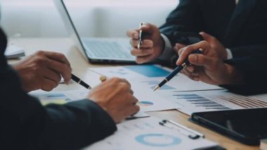 İş adamları yeni projeyi modern ofiste dizüstü bilgisayar ve iş belgeleriyle tartışıyor.