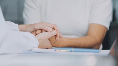 Genç bayan doktor hastanın elini tutuyor.