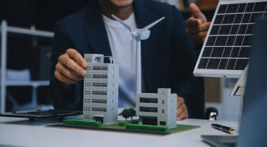 İki Genç Mühendis Güneş Hücresi Kurulum Toplantısı ve İş Tartışması Uzmanı. Ofis Odası 'nda Fabrika İnşaat Planlı Çatı Üzerine Güneş Fotovoltaik Panelleri Kurmayı Planlıyorum.