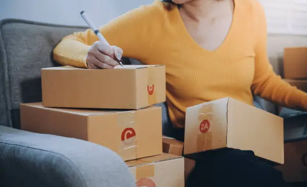 创业的小企业创业者或自由职业的亚洲女性使用装有盒子的笔记本电脑 年轻成功的亚洲女性举手投足 网上营销包装盒和送货 中小企业概念 — 图库照片