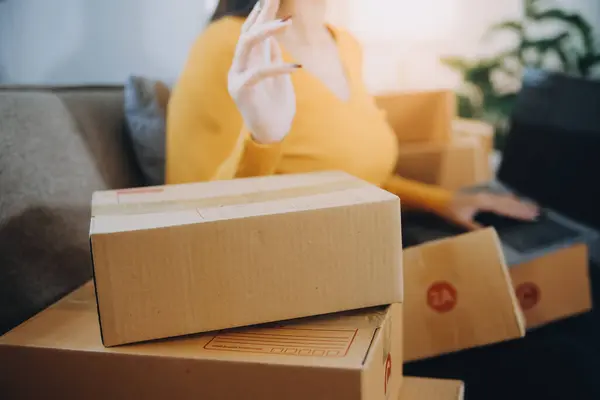 创业的小企业创业者或自由职业的亚洲女性使用装有盒子的笔记本电脑 年轻成功的亚洲女性举手投足 网上营销包装盒和送货 中小企业概念 — 图库照片