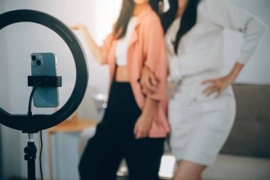 Asyalı genç bir kadın ve arkadaşı tiktoker akıllı telefon kamerasıyla dans videosunu çektiler. Sosyal medya uygulamasında video paylaşmak için