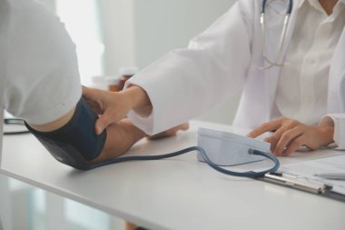 Erkek doktor, check-up, tıbbi tedavi ve sağlık konsepti için hastaneye gelen hastaların vücut basıncını ve nabzını ölçmek için kan basıncı monitörü kullanır..