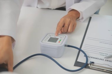 Erkek doktor, check-up, tıbbi tedavi ve sağlık konsepti için hastaneye gelen hastaların vücut basıncını ve nabzını ölçmek için kan basıncı monitörü kullanır..