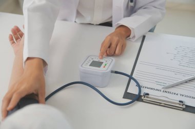 Erkek doktor, check-up, tıbbi tedavi ve sağlık konsepti için hastaneye gelen hastaların vücut basıncını ve nabzını ölçmek için kan basıncı monitörü kullanır..