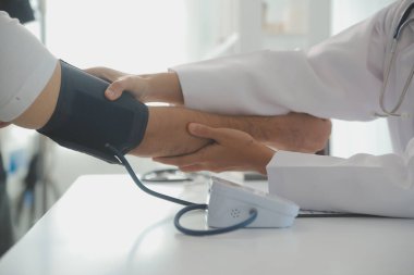 Erkek doktor, check-up, tıbbi tedavi ve sağlık konsepti için hastaneye gelen hastaların vücut basıncını ve nabzını ölçmek için kan basıncı monitörü kullanır..
