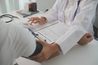 Erkek doktor, check-up, tıbbi tedavi ve sağlık konsepti için hastaneye gelen hastaların vücut basıncını ve nabzını ölçmek için kan basıncı monitörü kullanır..