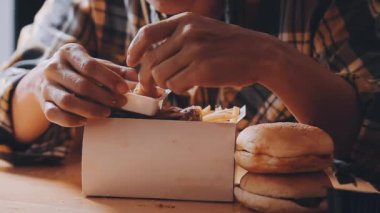 Tavuk, patates kızartması ve lezzetli hamburgerler yiyen adam.