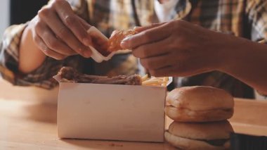 Hamburgerli tavuk ve patates kızartması yiyen bir kadın.
