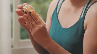 young woman eating sandwich and having breakfast in the morning.