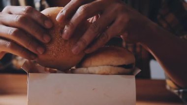 Arka planda hamburger yiyen kişi.