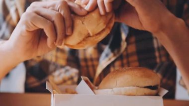 Arka planda hamburger yiyen kişi.