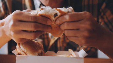 Arka planda hamburger yiyen kişi.