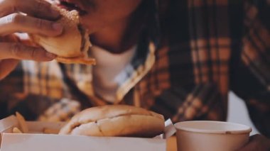 Arka planda hamburger yiyen kişi.