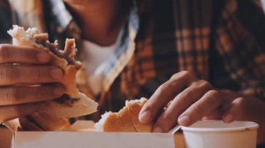 Arka planda hamburger yiyen kişi.