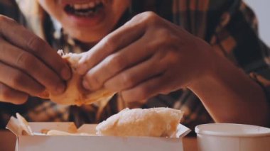 Arka planda hamburger yiyen kişi.