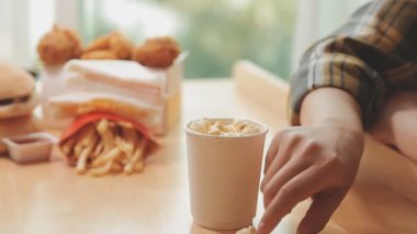 Elinde fast food tutan Asyalı bir kadın aşırı kilolu olma ve sağlıksız beslenmenin etkisini vurguluyor..