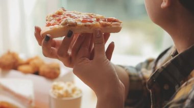 Kadın evde lezzetli abur cubur ve pizza yiyor.