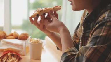 Kadın evde lezzetli abur cubur ve pizza yiyor.