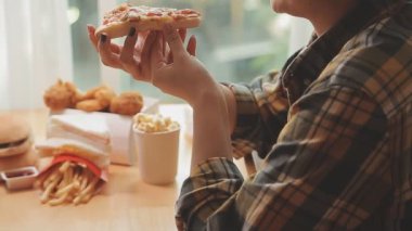 Kadın evde lezzetli abur cubur ve pizza yiyor.