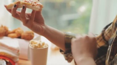 Kadın evde lezzetli abur cubur ve pizza yiyor.