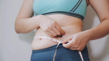 Bel ölçüsünü bantla alan genç bir kadın, kilolu olma kavramını gözler önüne seriyor..