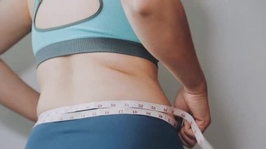 Bel ölçüsünü bantla alan genç bir kadın, kilolu olma kavramını gözler önüne seriyor..
