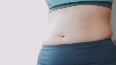 Bel ölçüsünü bantla alan genç bir kadın, kilolu olma kavramını gözler önüne seriyor..