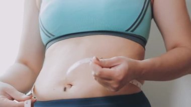 Bel ölçüsünü bantla alan genç bir kadın, kilolu olma kavramını gözler önüne seriyor..