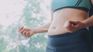 Bel ölçüsünü bantla alan genç bir kadın, kilolu olma kavramını gözler önüne seriyor..