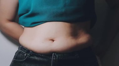 Kot pantolon giyen ve ölçü bandıyla bel ölçen genç bir kadın.