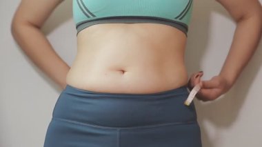 Daktilo yazan kadının kilolu konsepti ve kilo verme konsepti ölçü bandıyla belini ölçer.