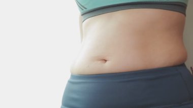 Daktilo yazan kadının kilolu konsepti ve kilo verme konsepti ölçü bandıyla belini ölçer.