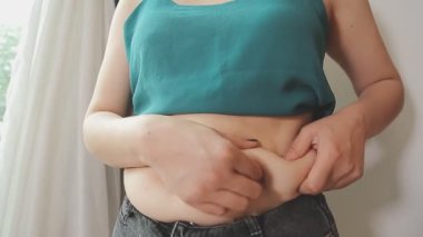 Obezite ve selülit. Kadın belinde aşırı yağ kıvrımları. Kilo verme, spor yapma, diyet ve yoğun eğitimin sonuçlarını kontrol etme kavramı. Kilo vermenin sonucu. Yağ aldırma