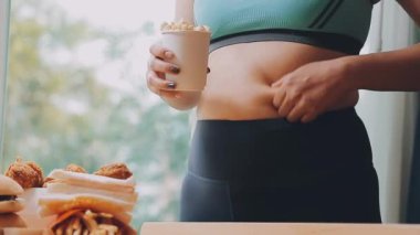 Elinde fast food tutan Asyalı bir kadın aşırı kilolu olma ve sağlıksız beslenmenin etkisini vurguluyor..
