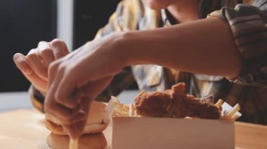 Tavuk kanadı ve kızarmış patates yiyen bir adam..