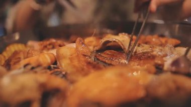 İnsanlar restoranda geleneksel Yakiniku usulü ızgara et ve karides pişiriyor..