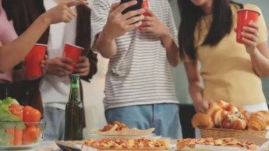 Bir grup genç arkadaş evde pizza yerken birayla eğleniyorlar. İnsanlar oturma odasında pizza içiyor..