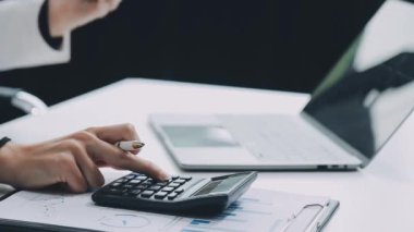 Ofiste çalışan işadamı, hesap makinesi ve finansal grafiği kullanıyor.